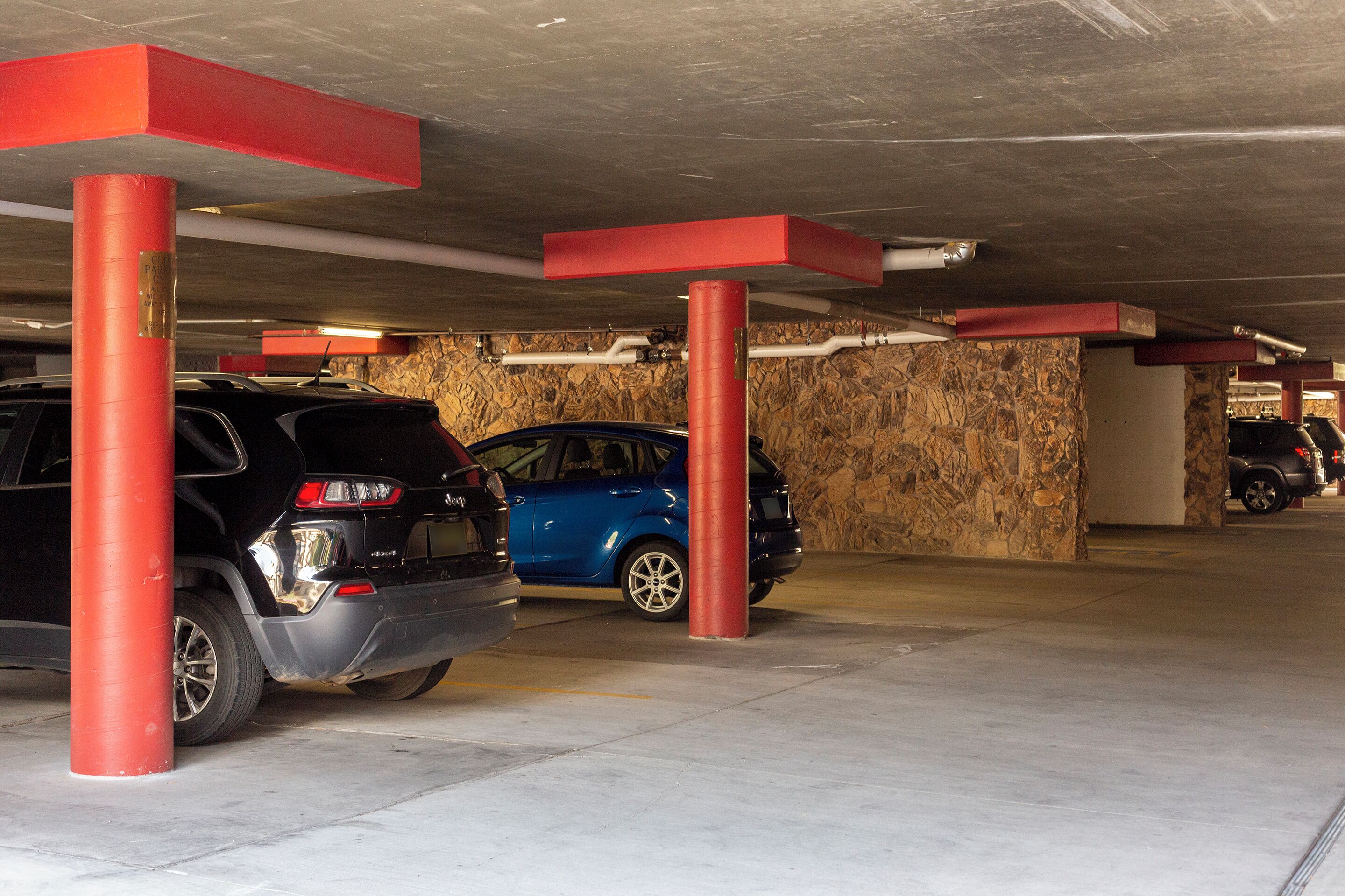 Eine Tiefgarage mit roten Säulen und einer Steinmauer.