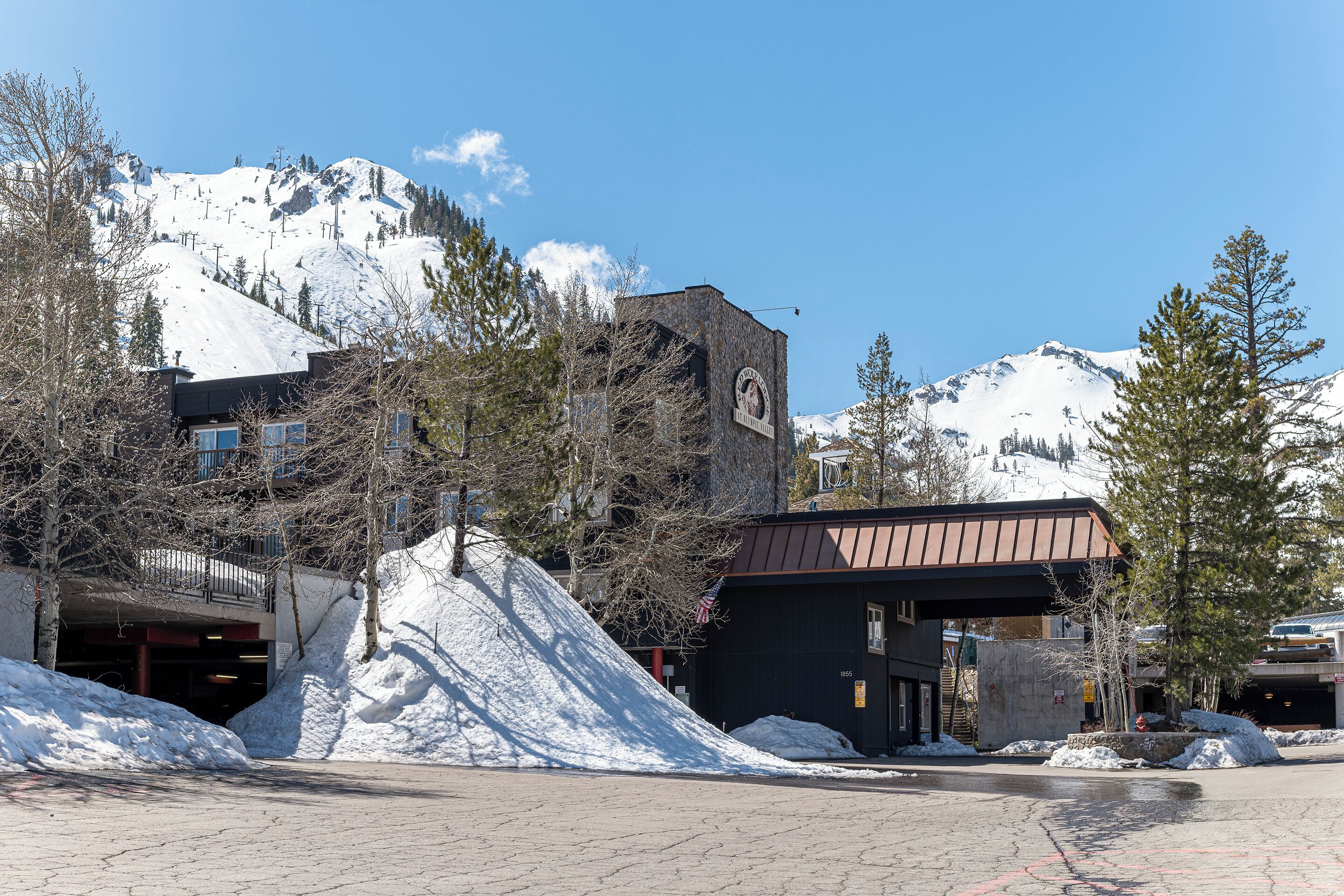 Un bâtiment doté d’un toit en métal et d’une grande horloge sur sa façade, entouré de neige et d’arbres.
