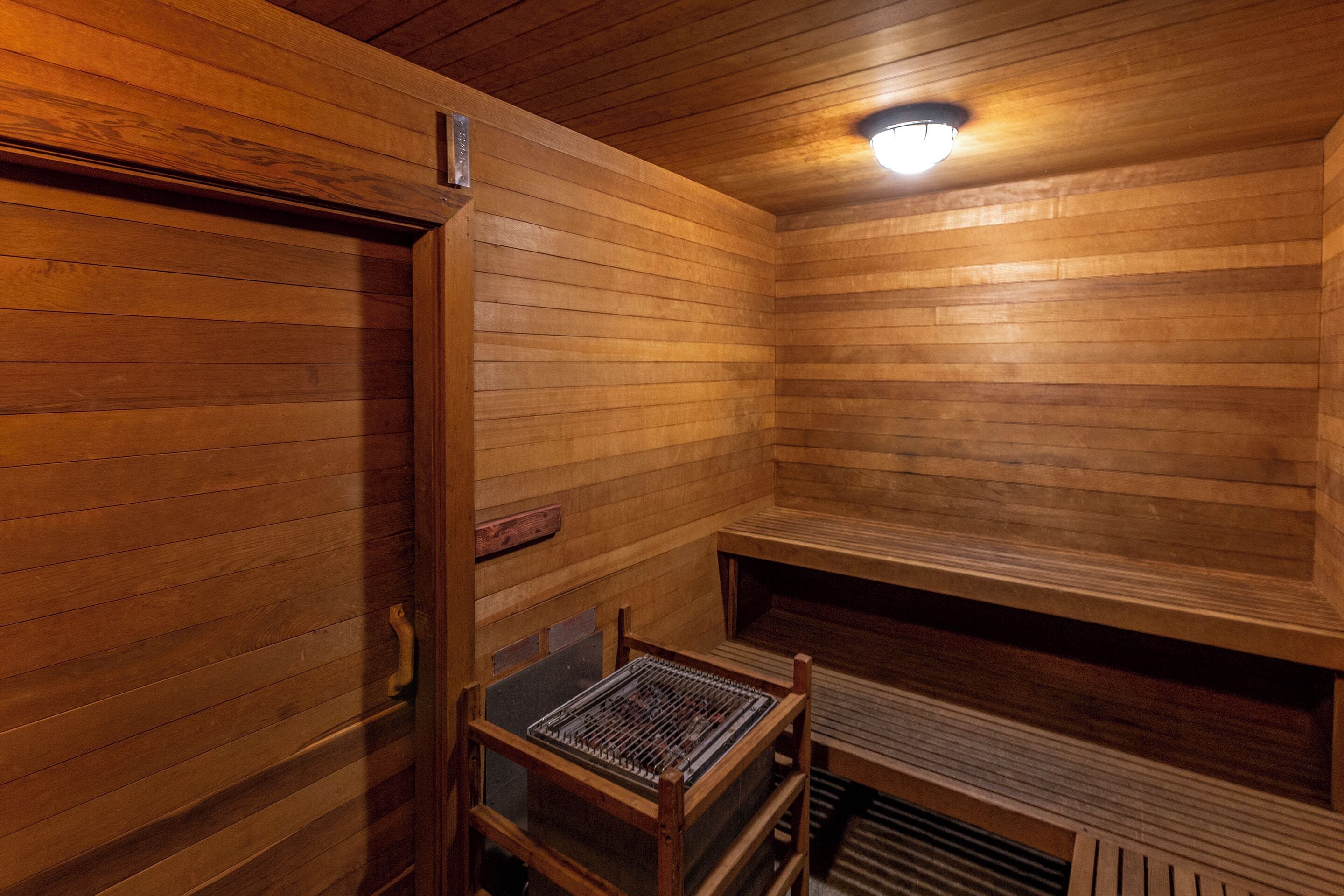 Una sauna de madera con un banco, una puerta y una lámpara.