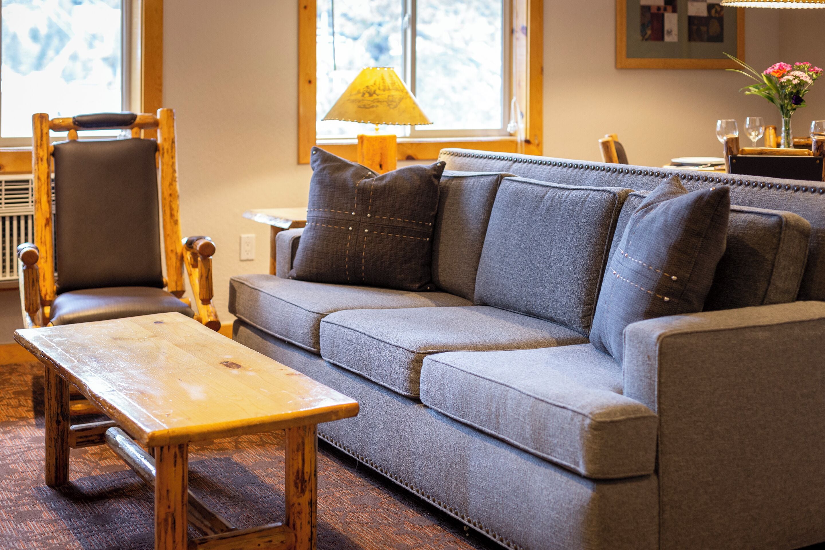 A cozy living room with a grey sofa, a wooden chair, and a small wooden table.