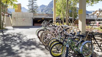 A parking area with bicycles parked under a shelter, a concrete wall, and a mountain view in the background.