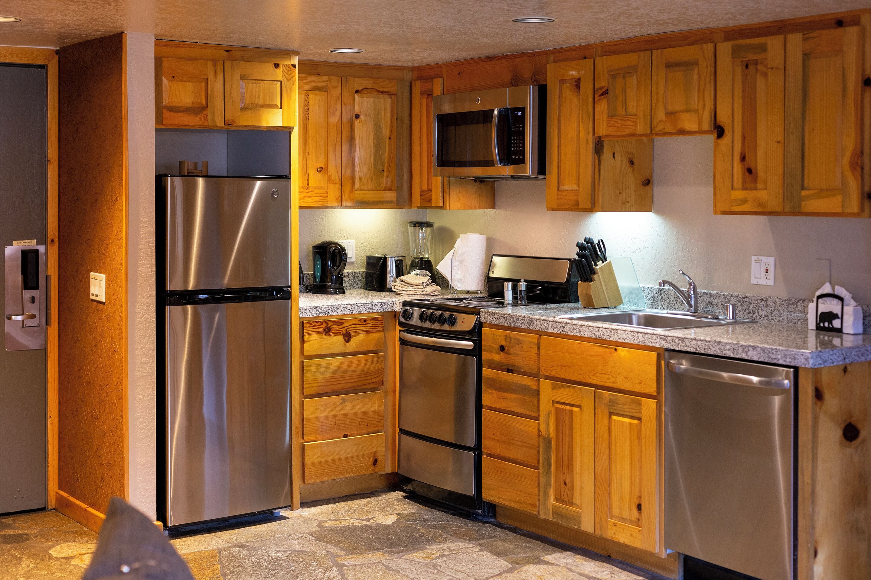 A kitchen with wooden cabinets, stainless steel appliances including a refrigerator, microwave, stove, and dishwasher.
