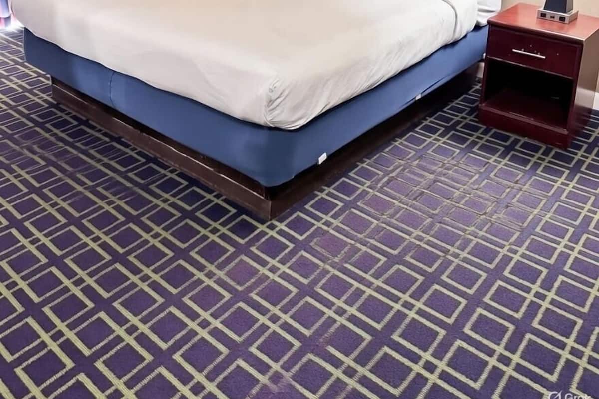 A hotel room with a large bed, two bedside tables, and a patterned carpet.