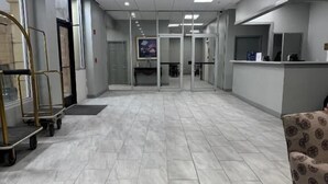 Un vestíbulo amplio con suelo de baldosas, una mesa de recepción y un área de estar.