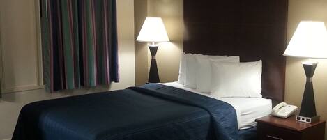 A hotel room with a bed, two bedside lamps, a telephone, and a striped curtain.