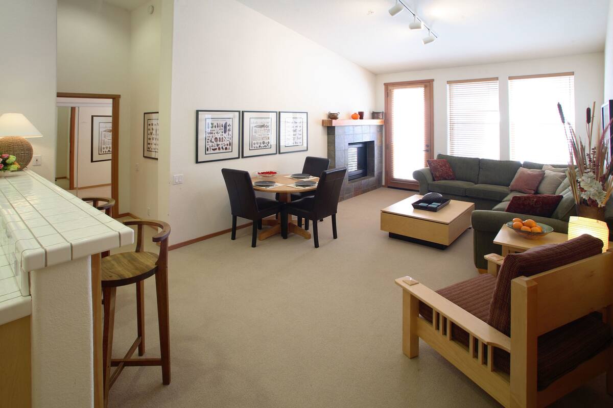 Uma sala de estar com área de jantar, lareira e sofá.