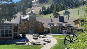 A building with a clock tower, outdoor seating, and a ski lift in the background.