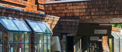 A wooden lodge with a glass conservatory and a mountain backdrop.
