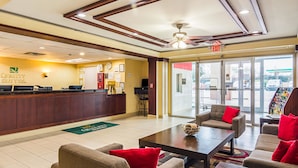 A hotel lobby with a reception desk, seating area, and a view of the outside. - Quality Suites Atlanta Airport East (Forest Park)