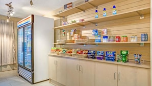 A hotel room with a minibar stocked with snacks, beverages, and toiletries. - Quality Suites Atlanta Airport East (Forest Park)