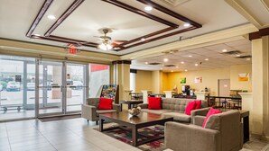 A lobby with a reception desk, seating area, and a view of the parking lot. - Quality Suites Atlanta Airport East (Forest Park)