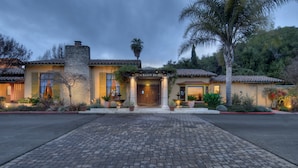 A hotel entrance with a cobblestone driveway, palm trees, and a stone facade. - Inn Marin and Suites, an Ascend Collection Hotel (Novato)