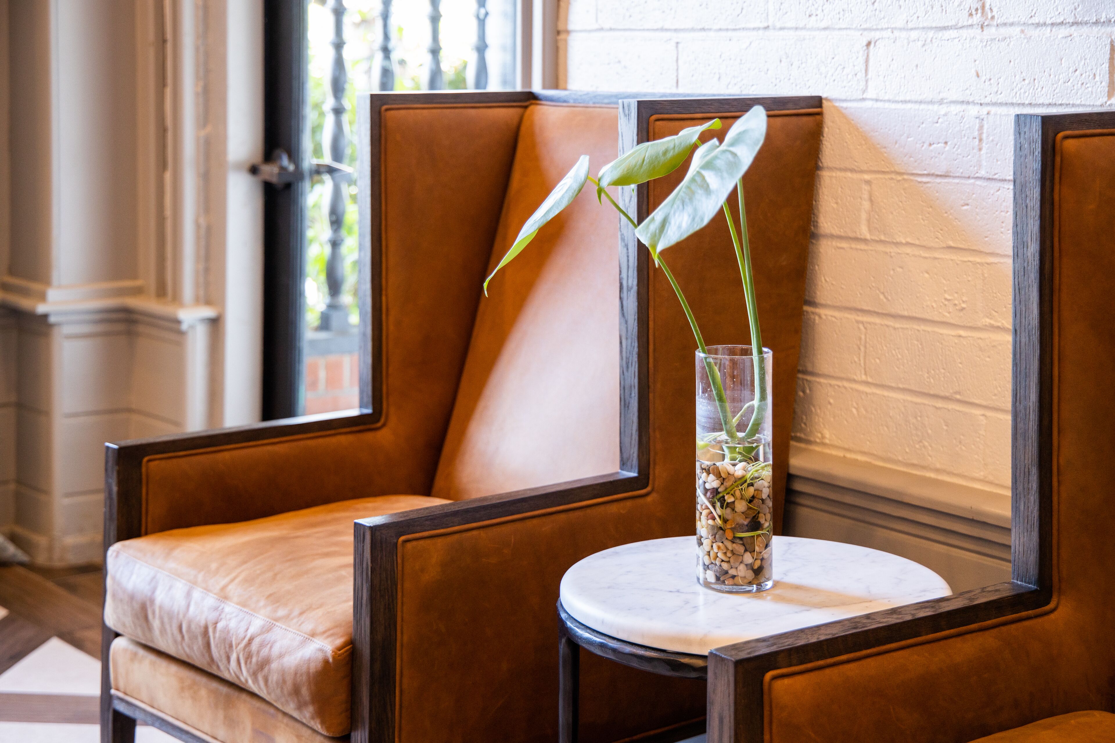 A seating area with a cushioned chair and a small table with a vase containing a plant.