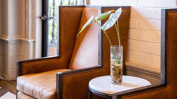 A seating area with a cushioned chair and a small table with a vase containing a plant.