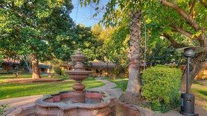 A garden with a stone fountain, a pathway, and a lamp post. - Inn Marin and Suites, an Ascend Collection Hotel (Novato)