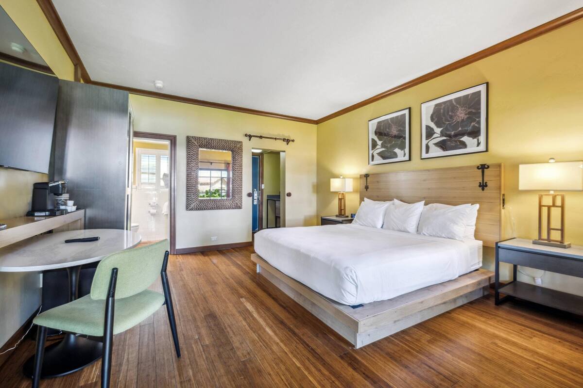 A hotel room with a bed, desk, chair, and a TV.