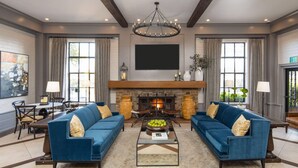 A spacious living room with a fireplace, two sofas, a coffee table, and a chandelier. - Inn Marin and Suites, an Ascend Collection Hotel (Novato)
