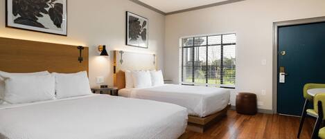 Une chambre d’hôtel avec deux lits, une fenêtre avec des stores, une porte et une chaise.