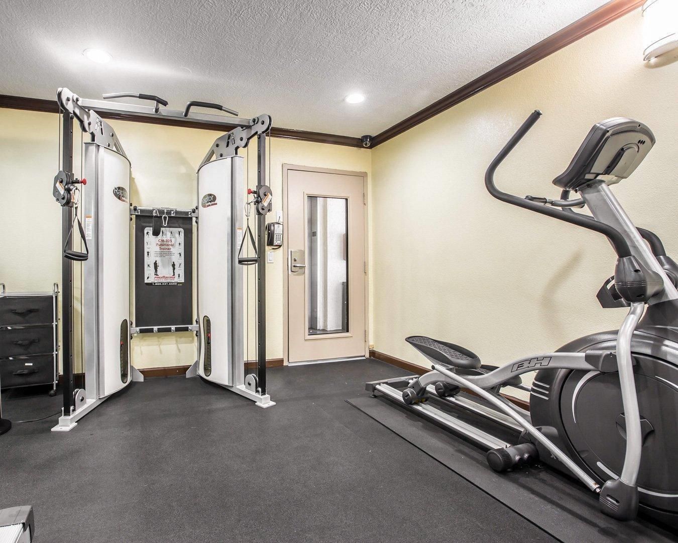 A gym with a treadmill, weight machines, and a mirror.