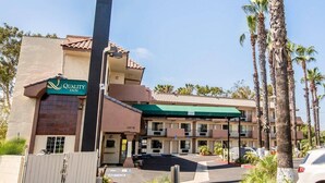 A Quality Inn hotel with a green sign, multiple balconies, and a parking lot. - Quality Inn San Diego I-5 Naval Base (San Diego)