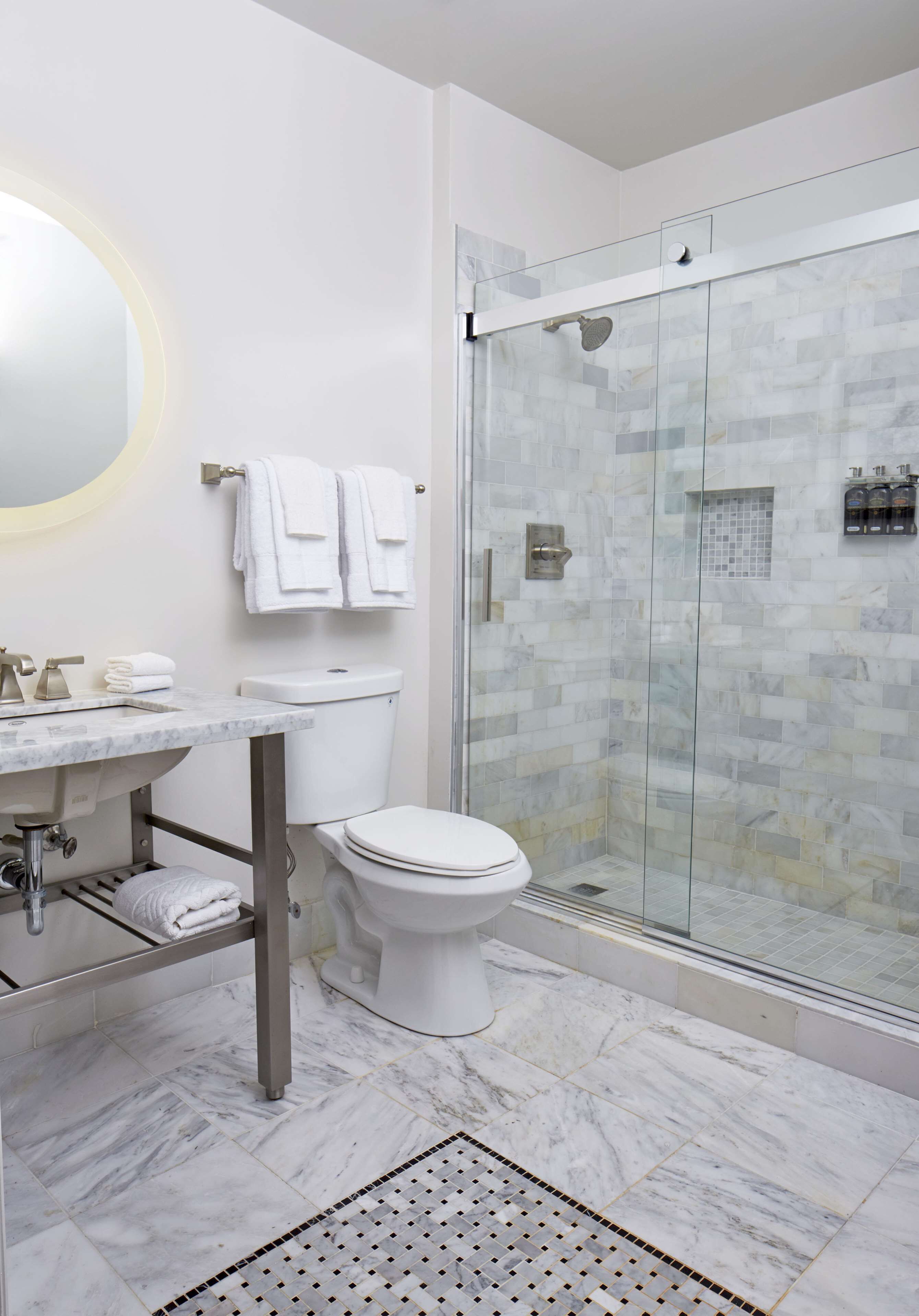 A modern bathroom with a glass-enclosed shower, a marble sink, and a toilet.