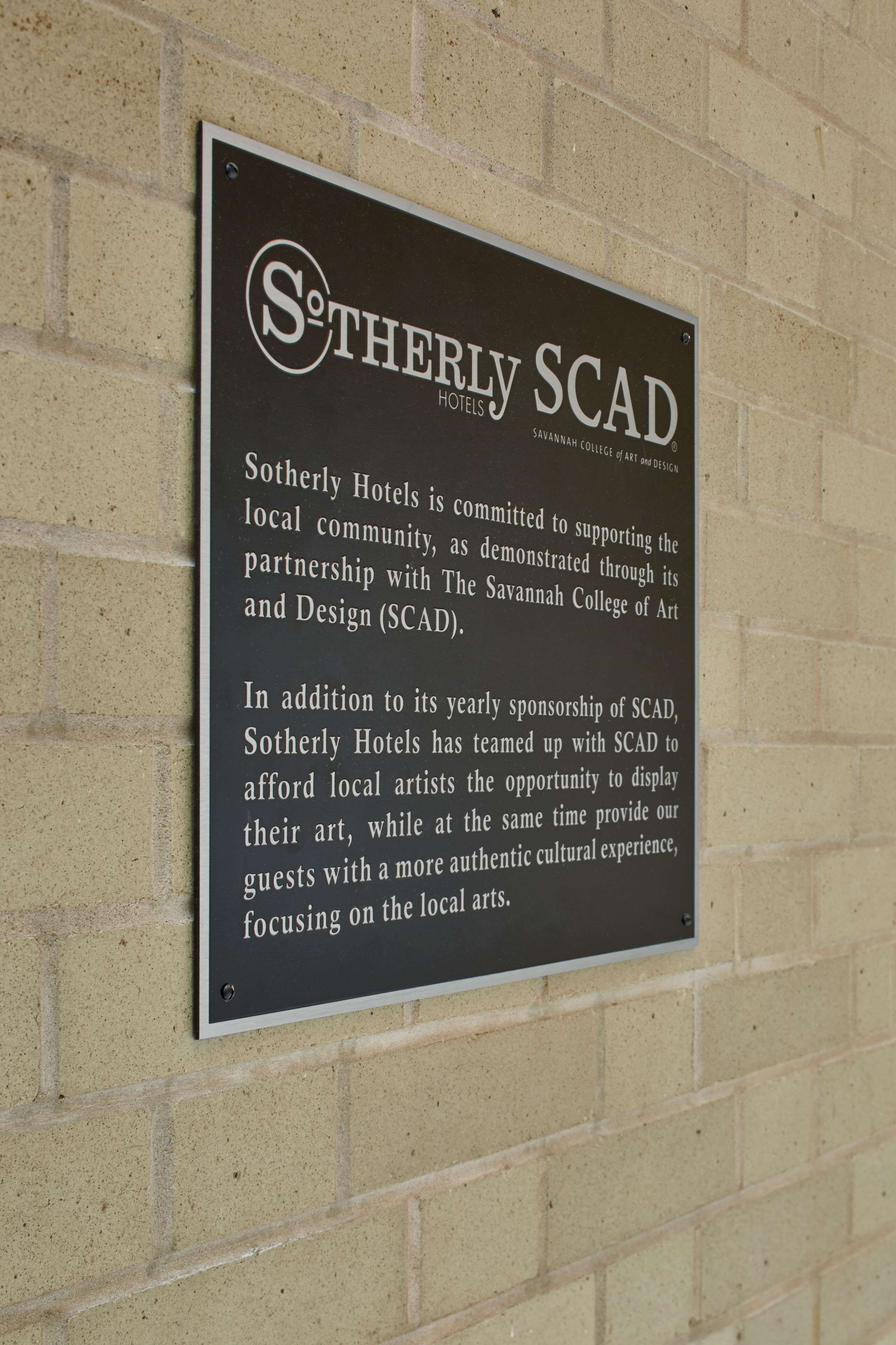 A sign for Sotherly Scad Hotels detailing their commitment to supporting the local community and partnership with The Savannah College of Art and Design (SCAD).