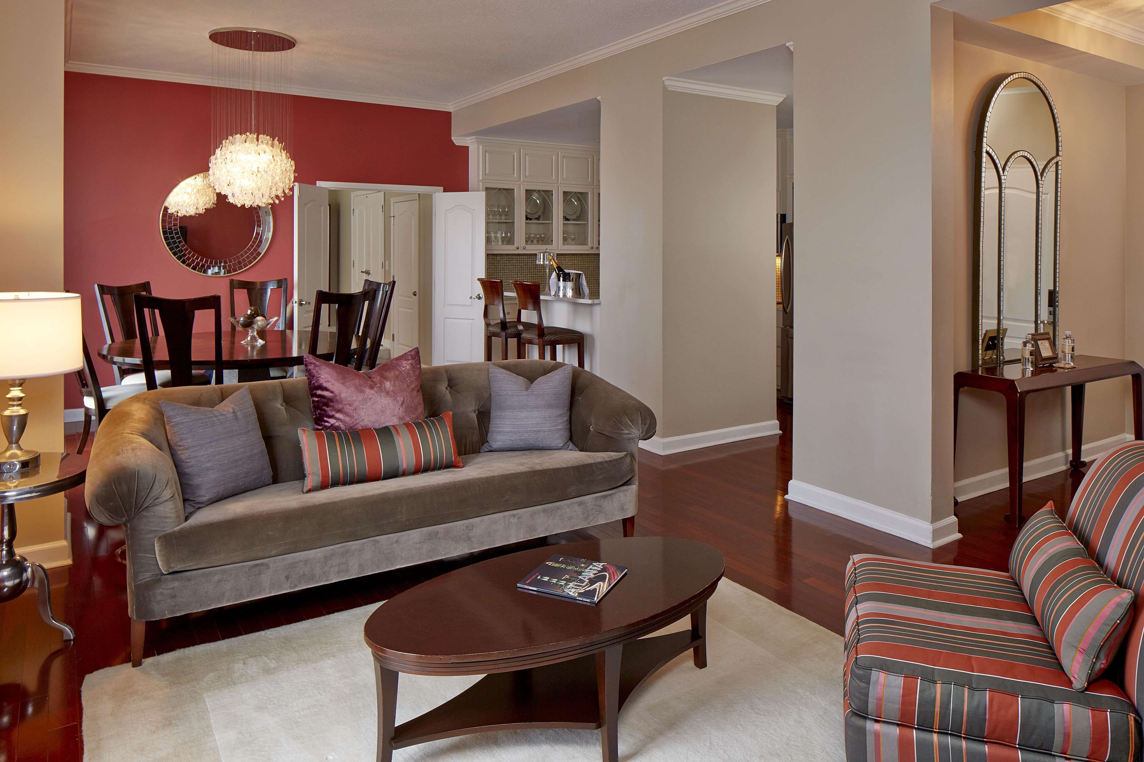 A living room with a sofa, armchair, coffee table, and a dining area with chairs and a table.