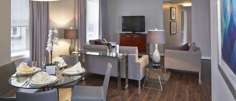 Een moderne hotelkamer met een zithoek, een bank, een televisie en een schilderij aan de muur.