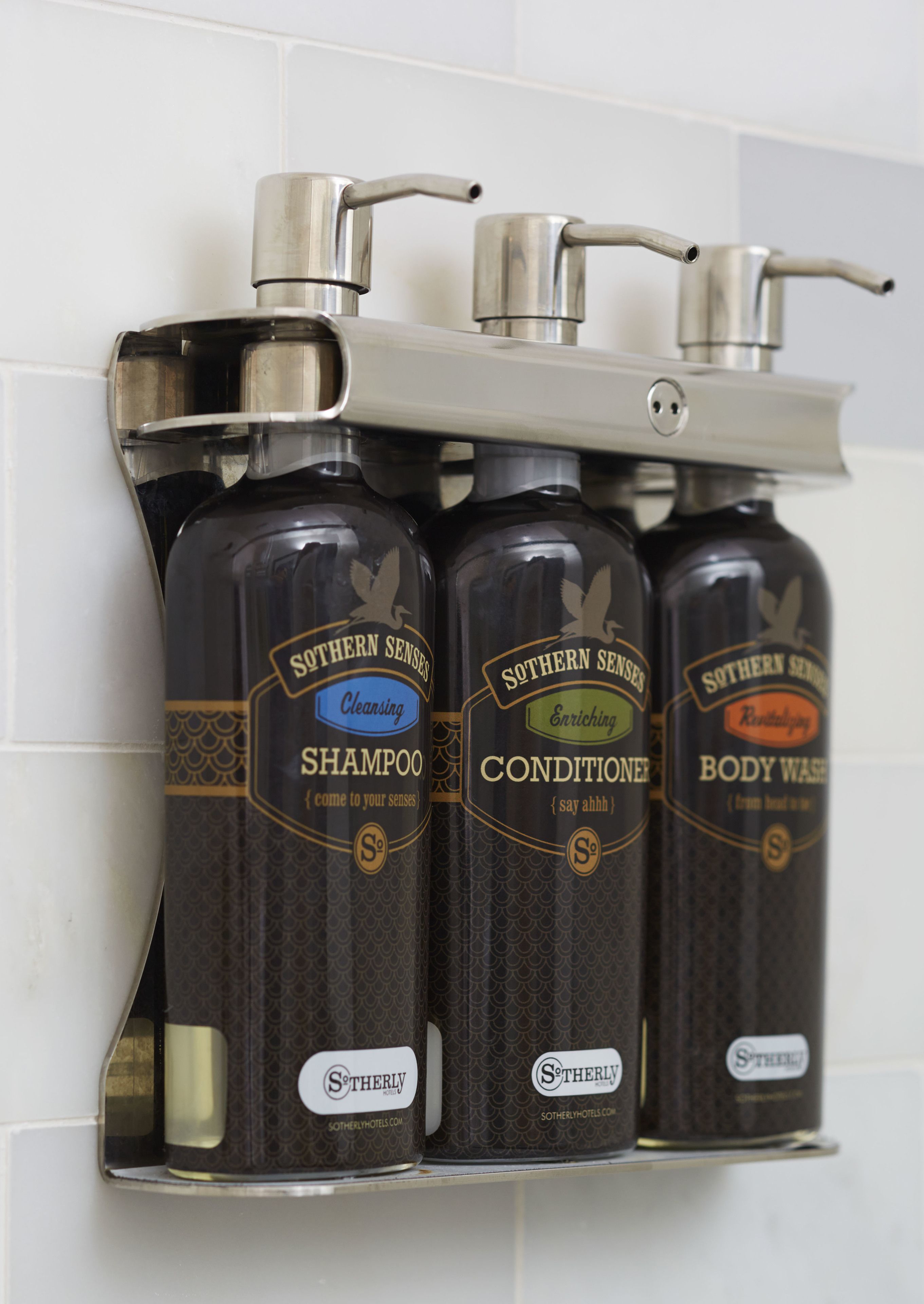 Tres botellas de productos Southern Senses: champú, acondicionador y gel de baño, sujetas a una pared.