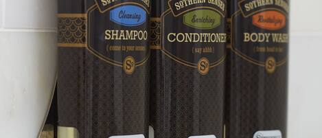 Tres botellas de productos Southern Senses: champú, acondicionador y gel de baño, sujetas a una pared.