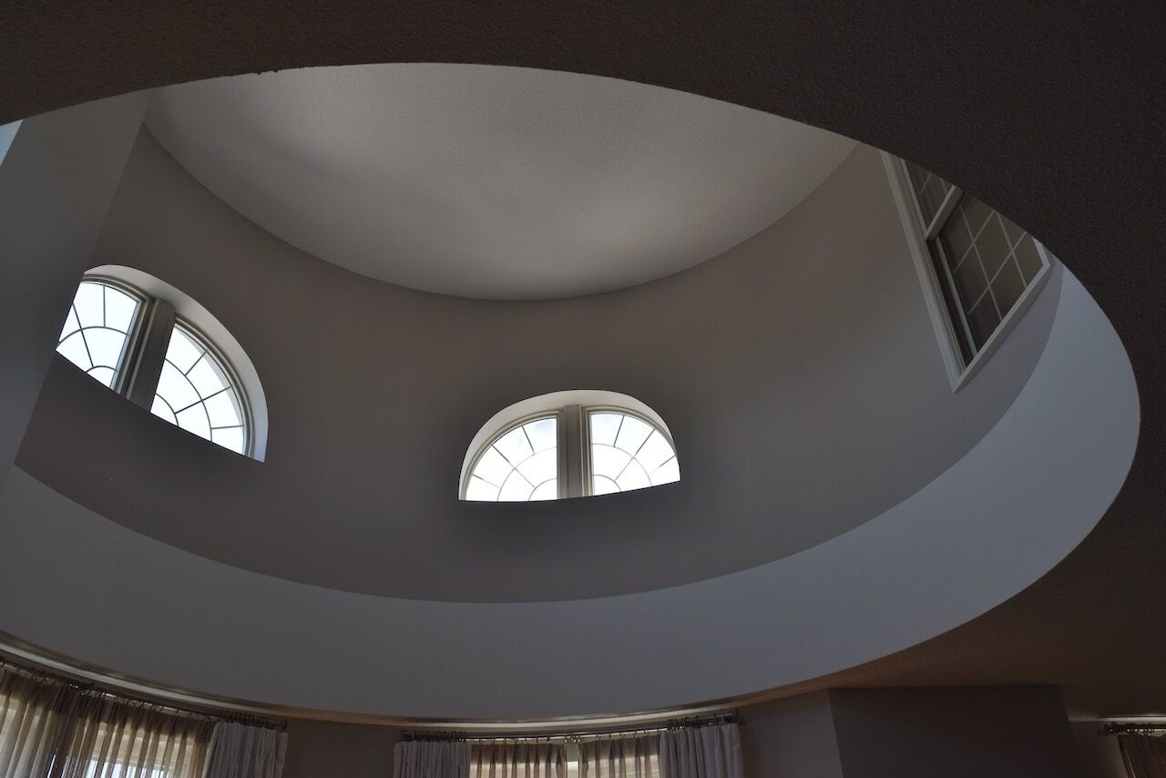 A curved ceiling with three arched windows allowing natural light into a spacious room.