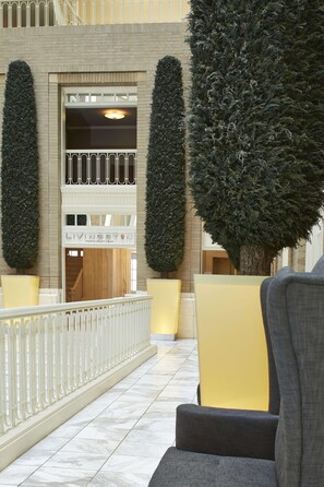 A lobby with a double-height entrance, a staircase, and a seating area with yellow chairs.