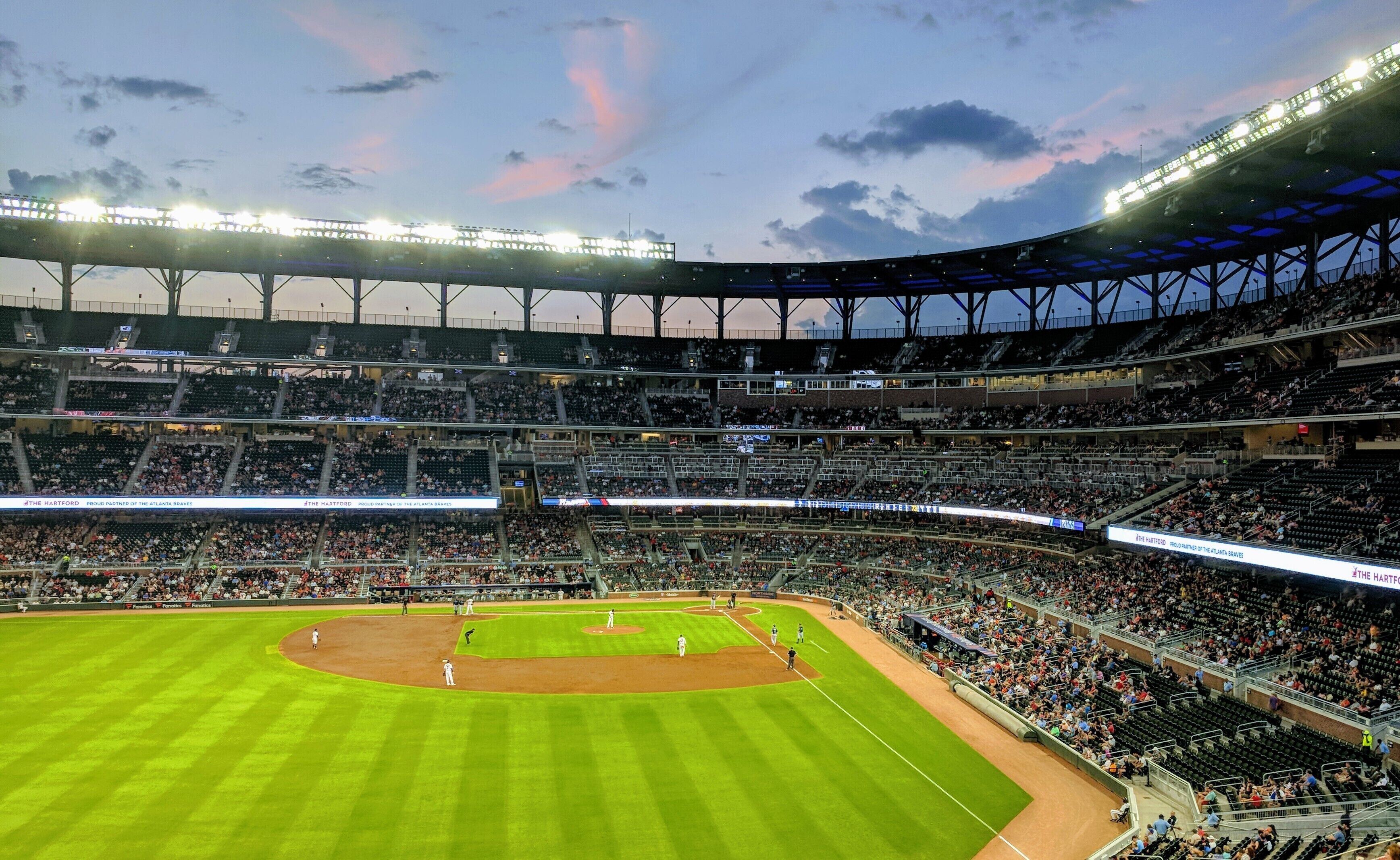 A large stadium with multiple levels of seating, a baseball field, and a clear sky.