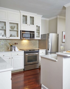 A kitchen with white cabinetry, a stainless steel oven, a microwave, and a refrigerator.