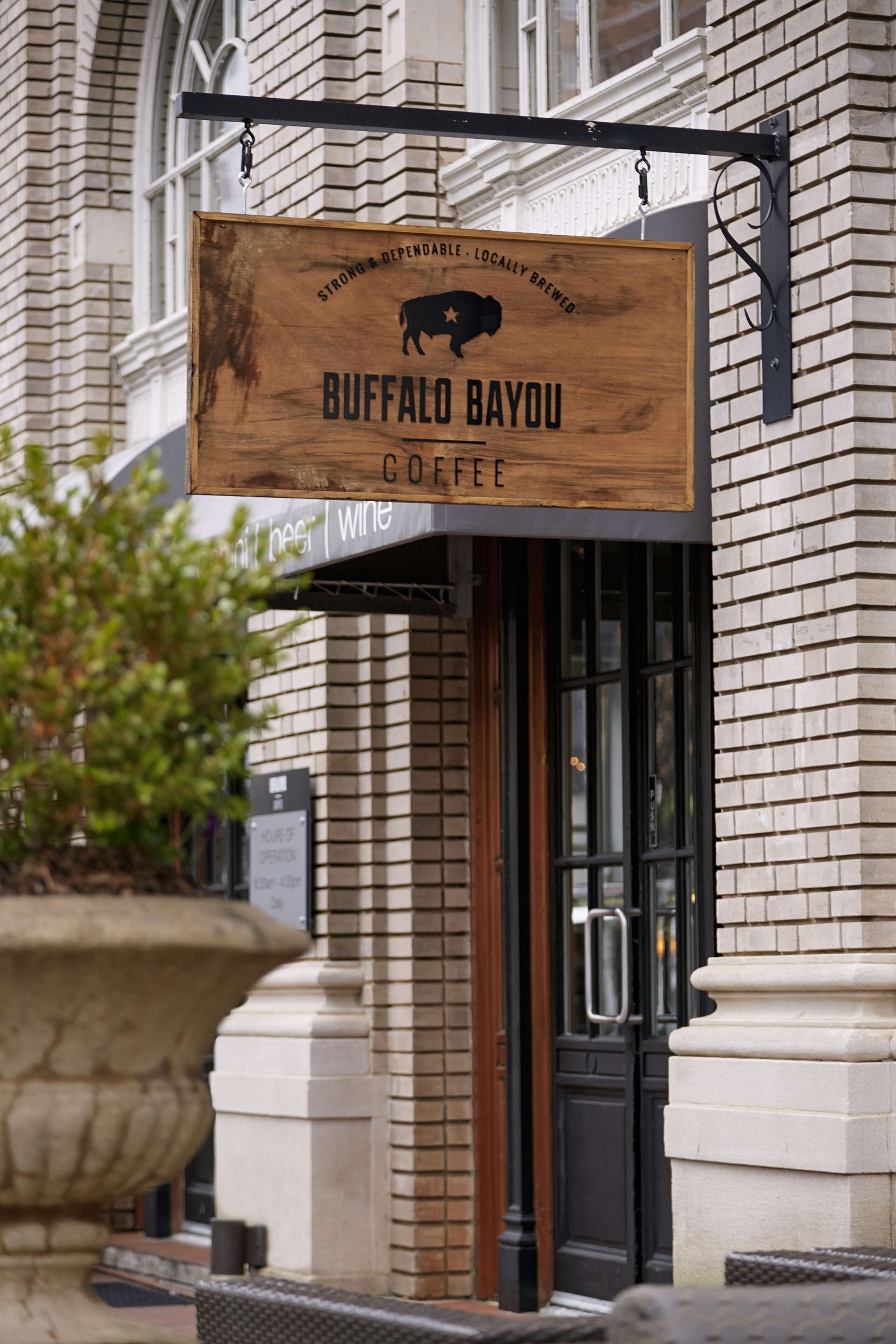 Une enseigne en bois pour le café Buffalo Bayou, avec un support en métal noir.