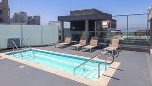 A rooftop pool with lounge chairs and a glass-enclosed structure.