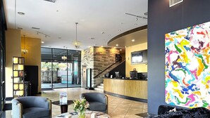 A lobby with a reception desk, seating area, and a large abstract painting.