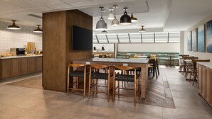 Un restaurante moderno con una barra central, mobiliario de madera e iluminación colgante.