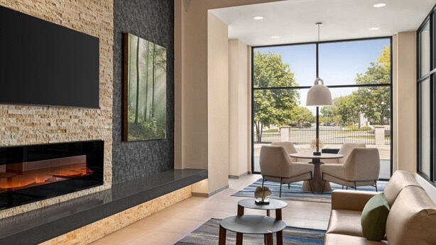 Una sala de estar moderna con chimenea, un televisor de pantalla plana y un ventanal con vistas al exterior.