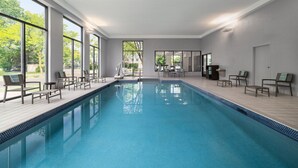Una piscina con sillones de descanso y vistas a zonas verdes.