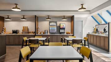 A modern restaurant with a bar area, wooden tables and chairs, and pendant lighting.