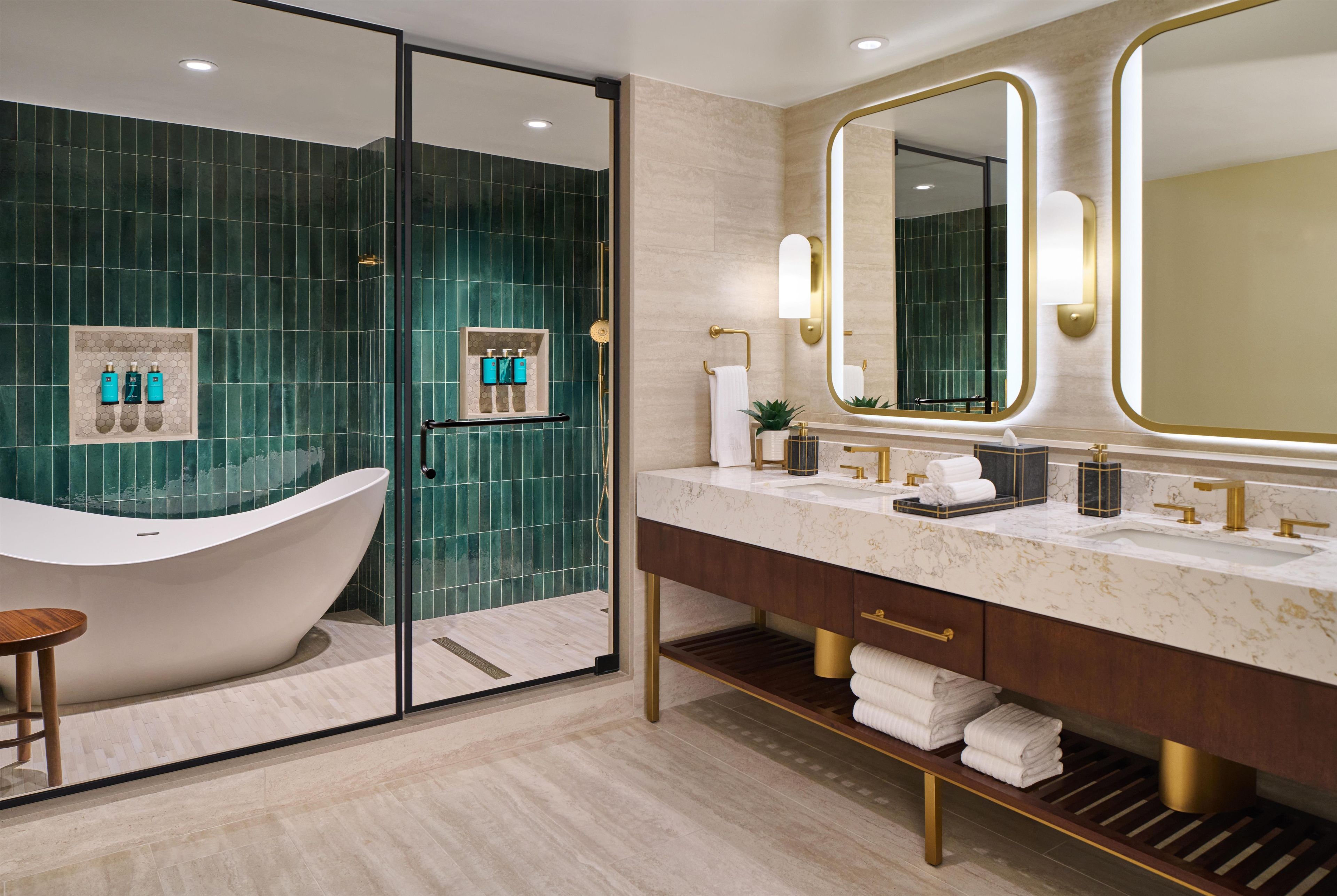 A modern bathroom with a freestanding bathtub, a vanity with a large mirror, and a shower area.