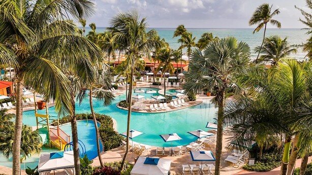 A resort with a large pool area, palm trees, and a view of the ocean. - Wyndham Grand Rio Mar Rainforest Beach and Golf Resort (Río Grande)