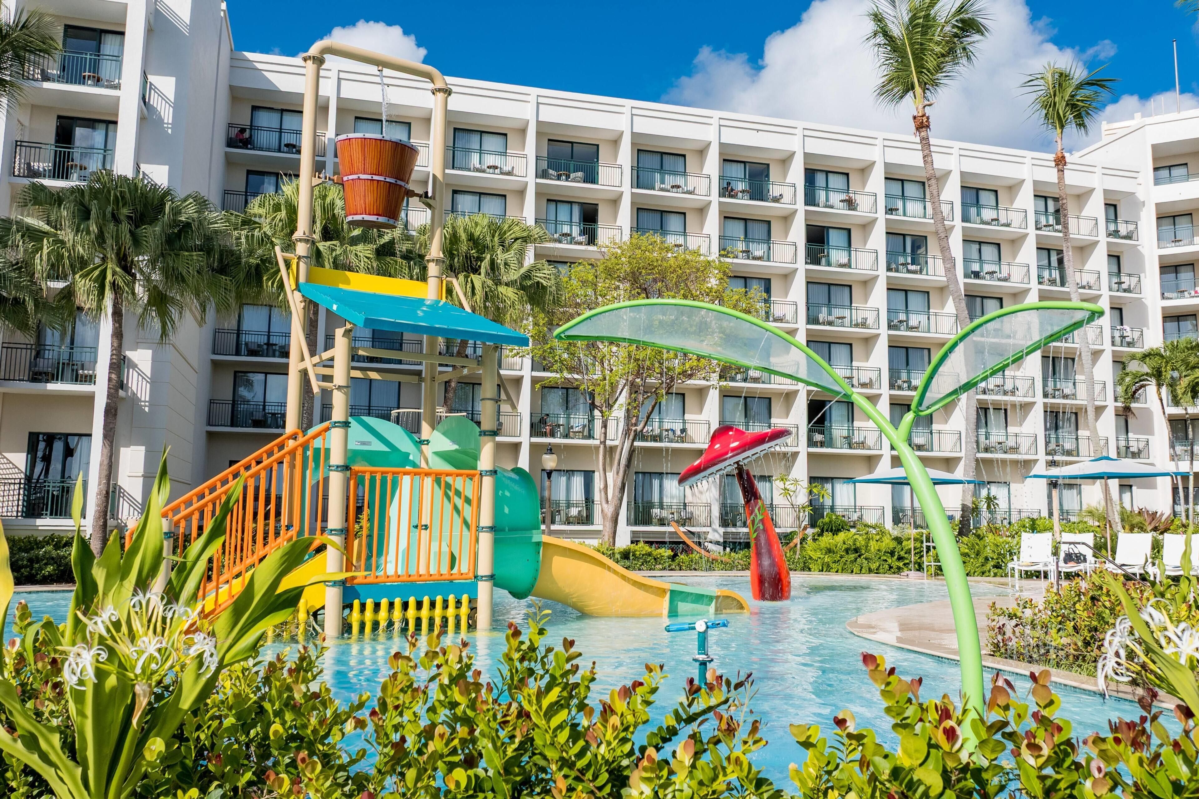 Un hotel con zona de piscina que incluye un tobogán de agua y estructuras de juegos.