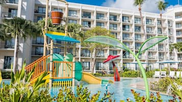 Un hotel con zona de piscina que incluye un tobogán de agua y estructuras de juegos.