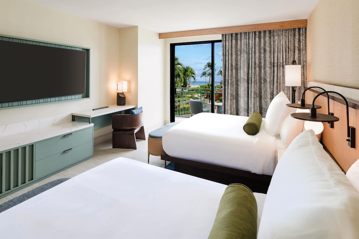 A hotel room with a bed, a desk, a chair, a TV, and a view of the outdoors.