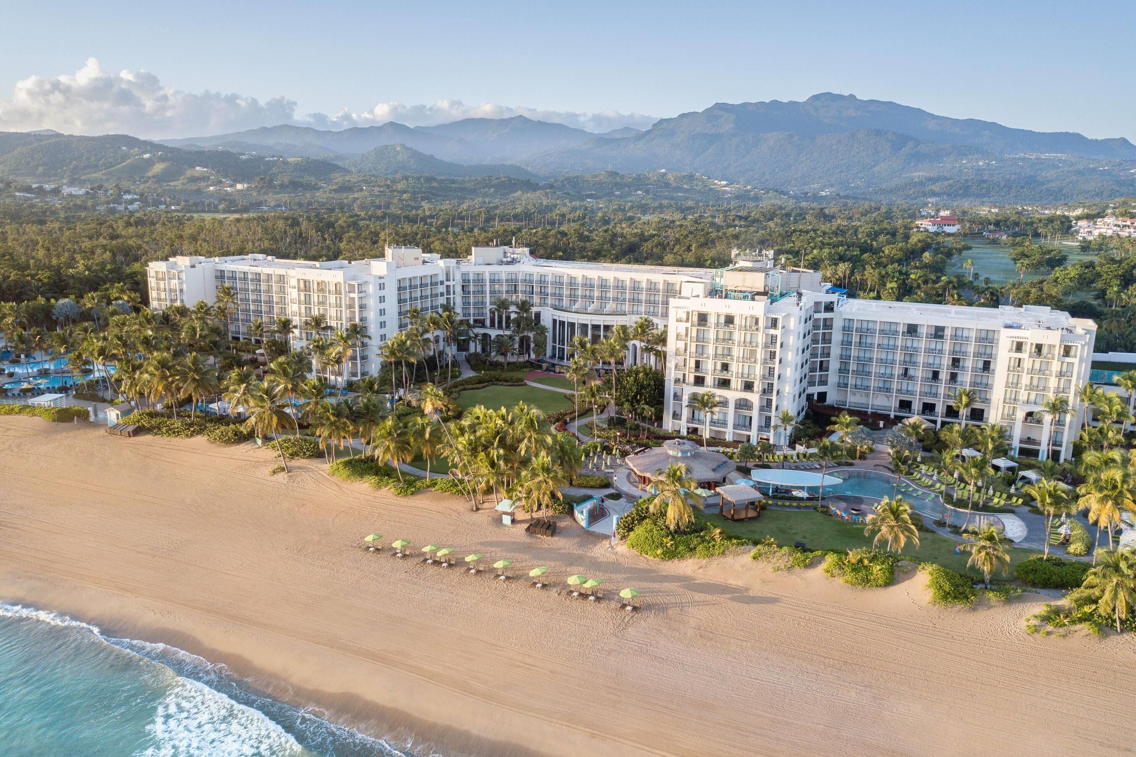 A resort with multiple buildings, a beach, and palm trees.