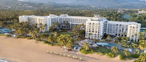 A resort with multiple buildings, a beach, and palm trees.
