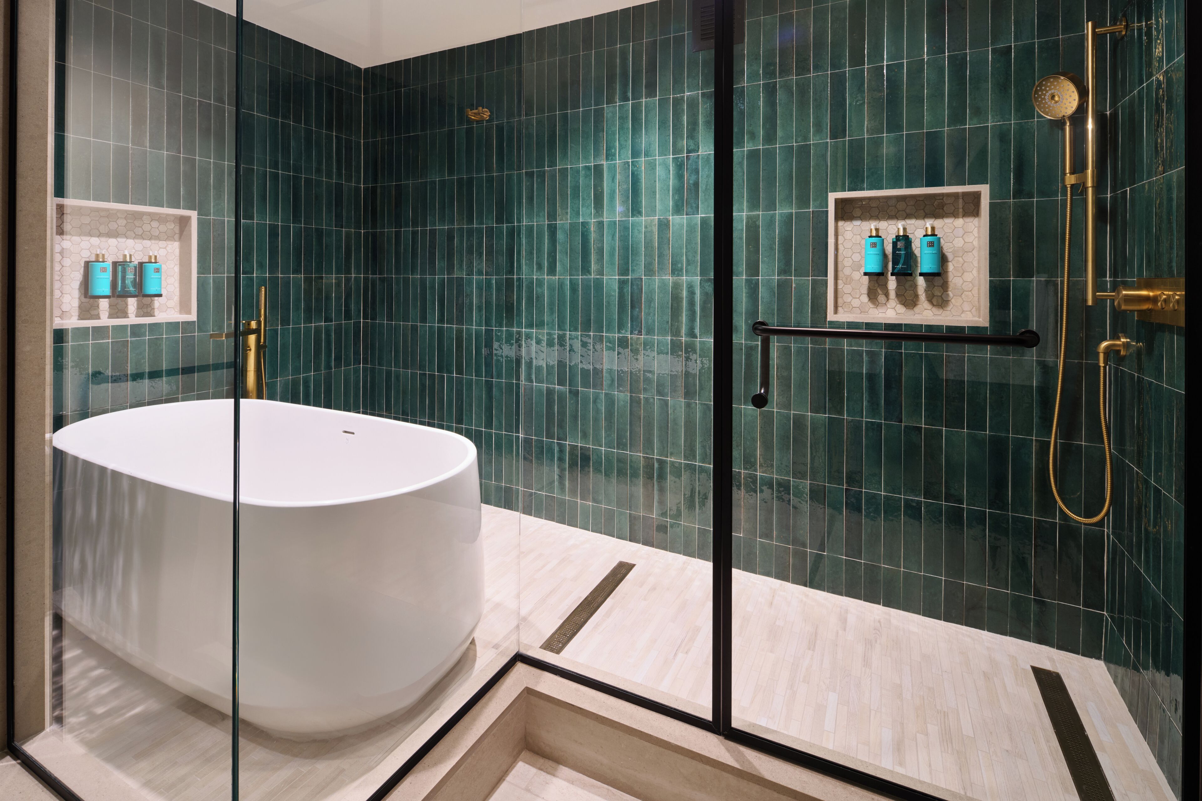 A modern bathroom with a freestanding bathtub, a glass-enclosed shower area, and a shelf with toiletries.