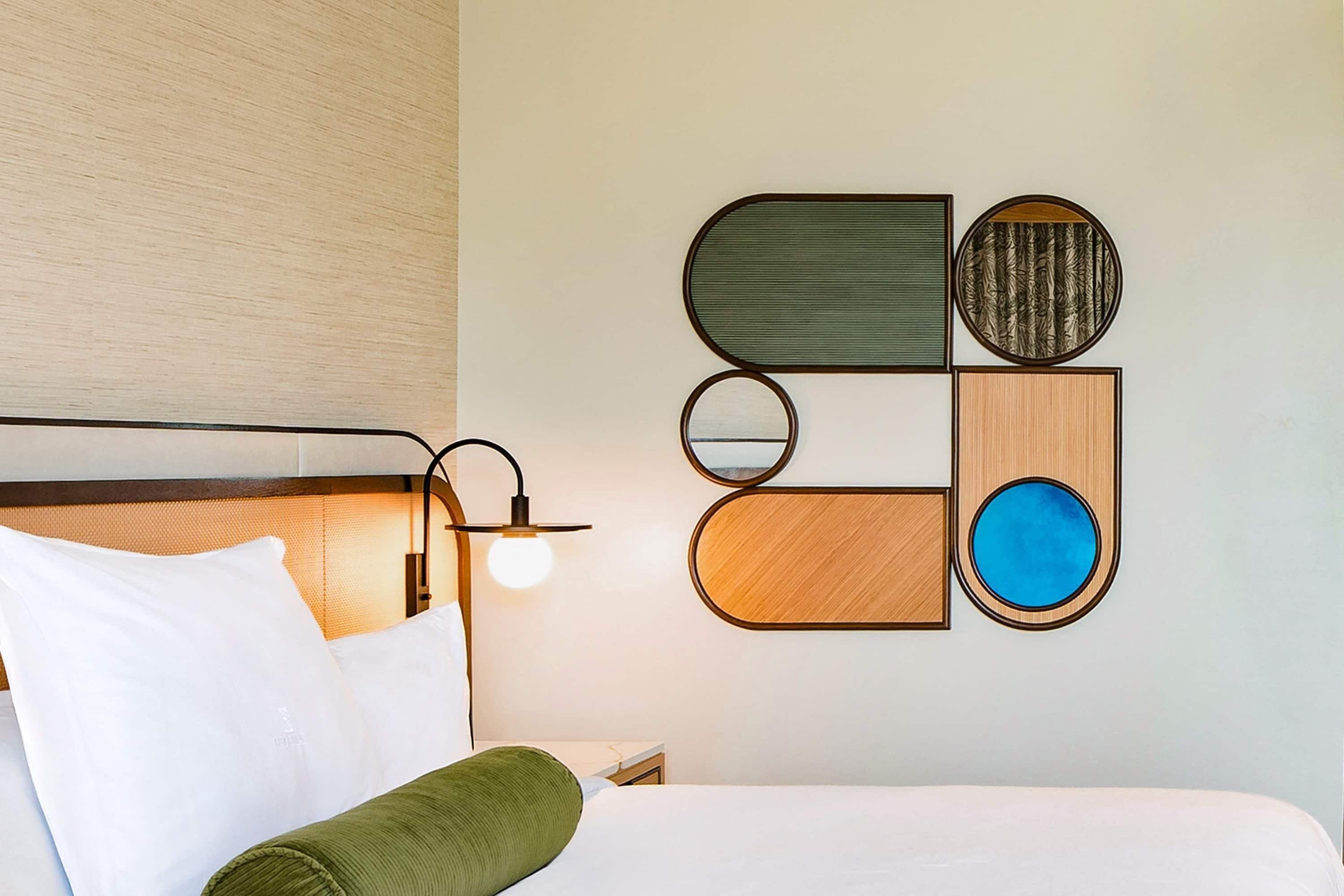 Una habitación de hotel con cama, mesita de noche, lámpara y decoración en la pared.
